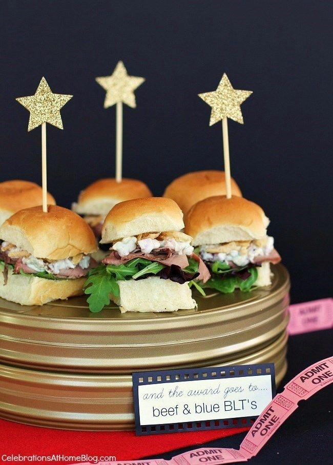 mini sandwiches with toothpicks in them on a gold plate next to pink ribbon