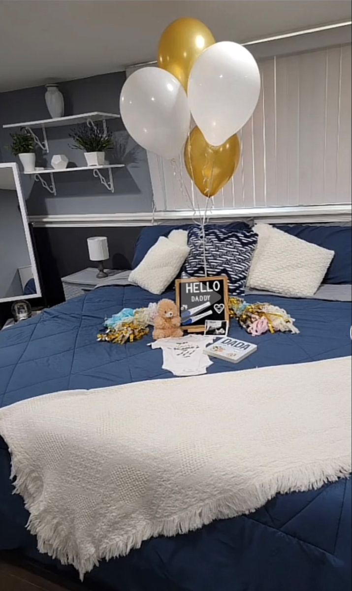 a bed with white and gold balloons on top of it