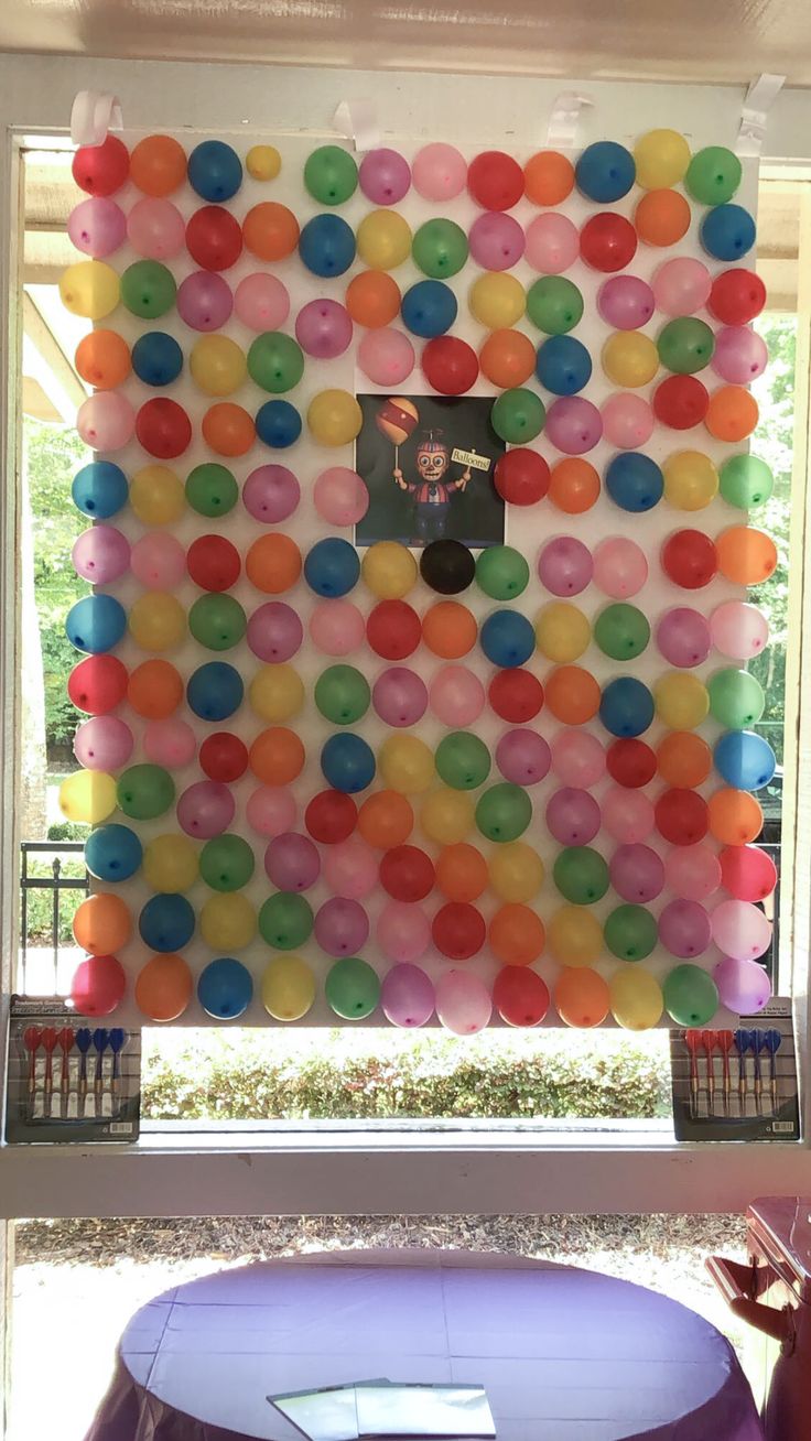 a wall made out of balloons with a clock on it