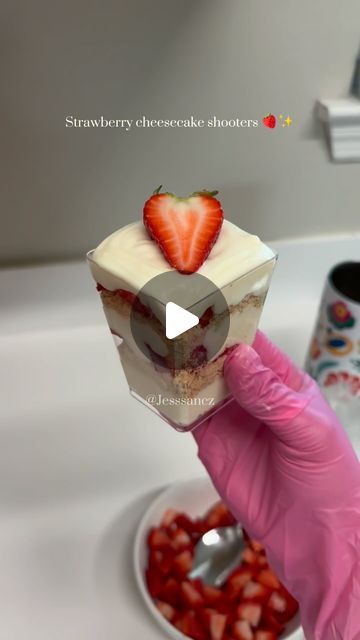 a person in pink gloves holding up a piece of cake with strawberries on it