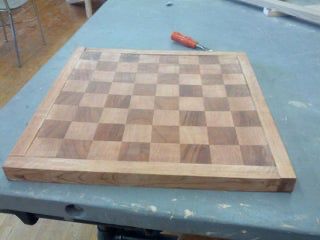 a wooden chess board sitting on top of a blue table next to a knife and fork