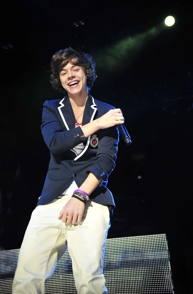 a young man sitting on top of a white bench in front of a stage holding a microphone