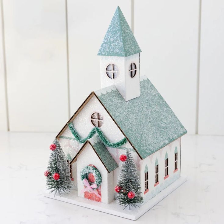 a small white church with christmas decorations on the roof and steeple is shown in front of a white background