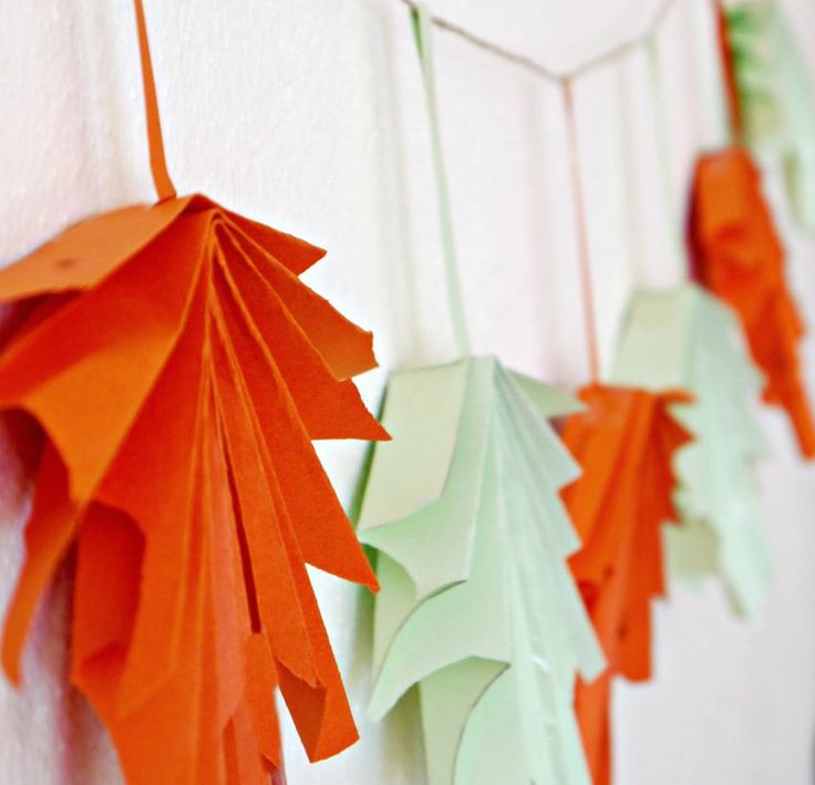 paper leaves are hanging on the wall next to a white board with orange and green decorations