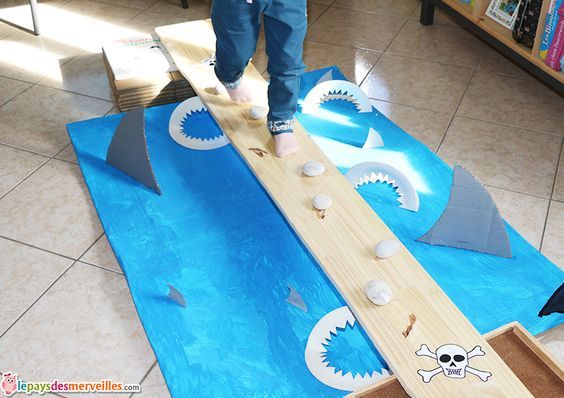 a child is playing with a wooden toy in the middle of a play area that looks like a shark