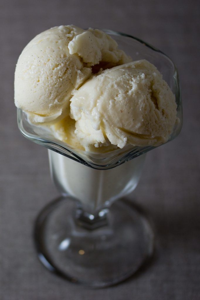 two scoops of ice cream sit in a glass dish on a gray tablecloth