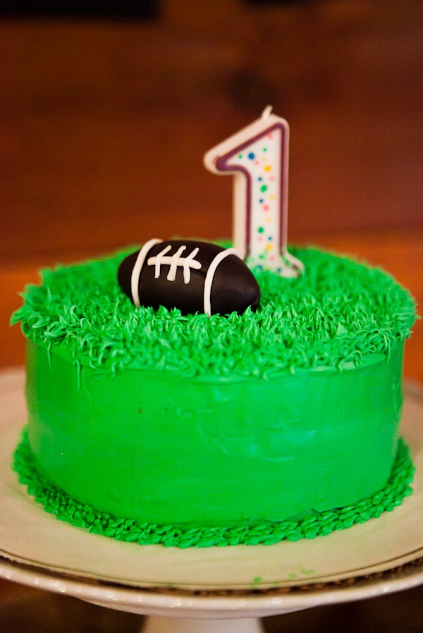 a birthday cake decorated with green frosting and a football on the top is one