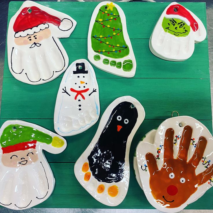 paper plates with handprinted christmas decorations on them sitting on a green tablecloth