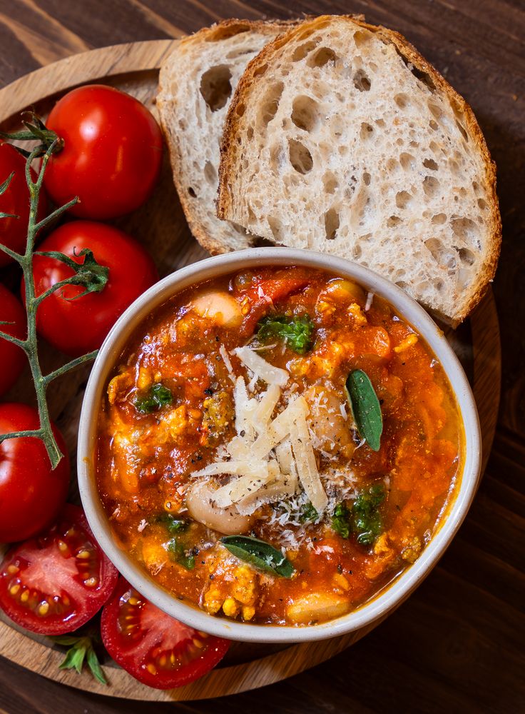 a bowl of soup with bread and tomatoes