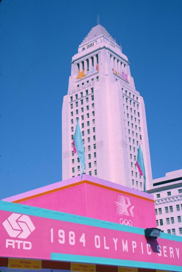 a large pink building with a clock on it's side in front of other tall buildings