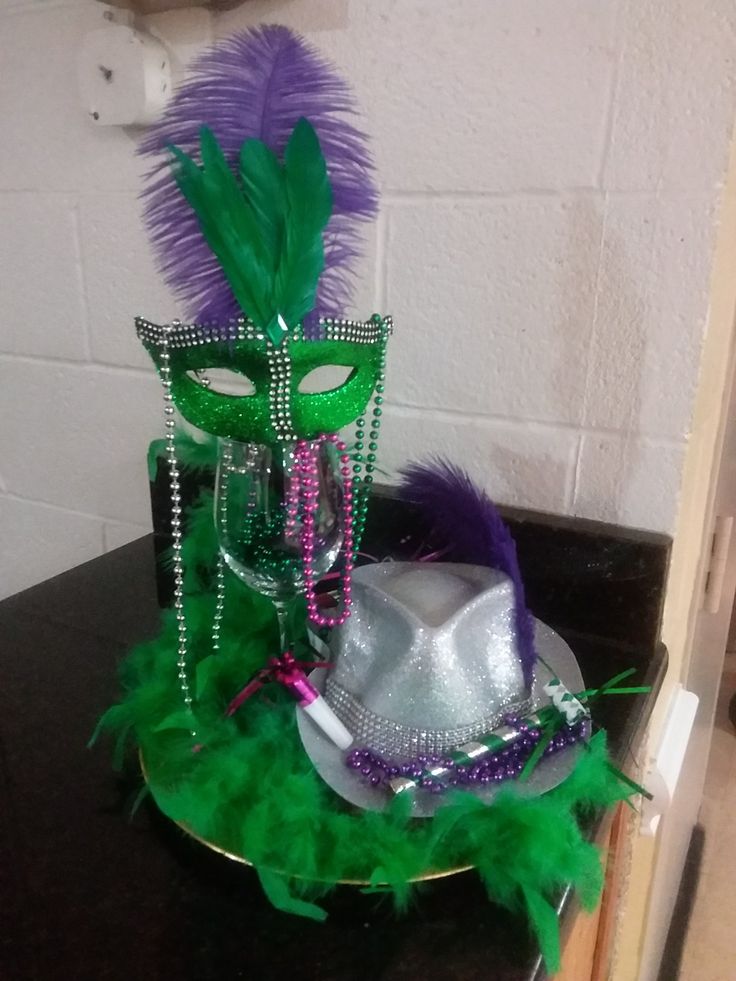 two mardi gras masks are sitting on a table with green and purple feathers