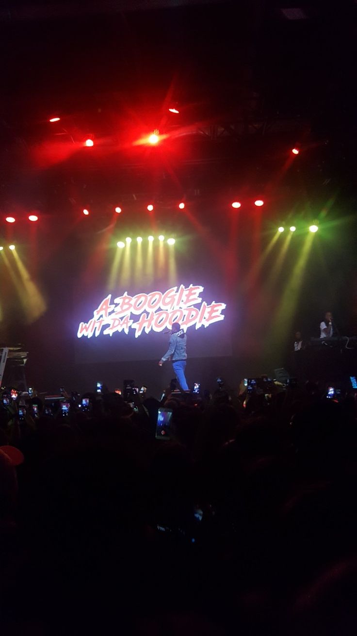 a man standing on top of a stage in front of bright colored lights and people