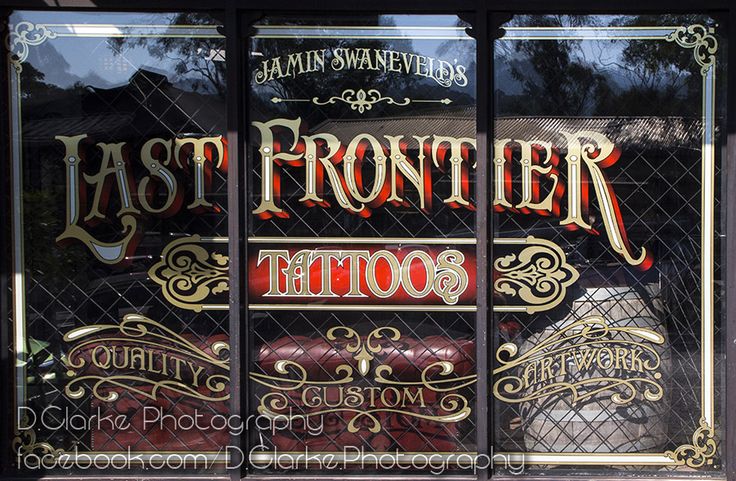 the front window of a tattoo parlor with ornate lettering on it's glass windows