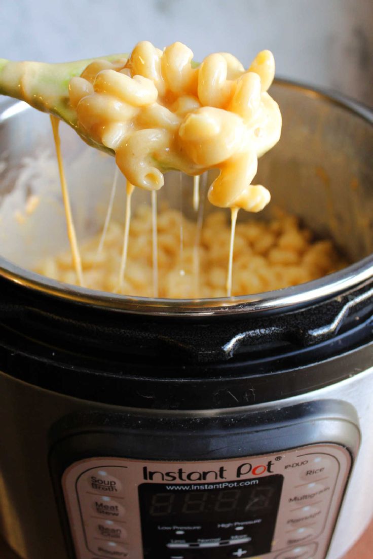 a spoon full of macaroni and cheese being lifted from an instant pot