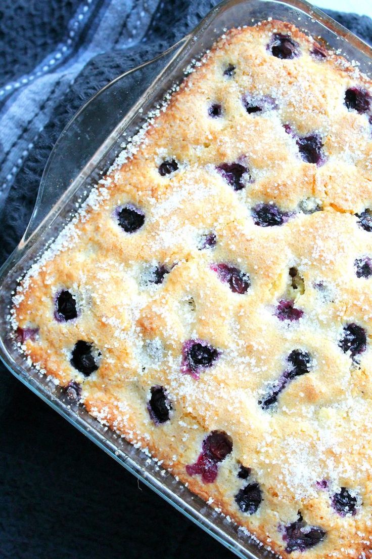 a blueberry cobbler in a glass dish with powdered sugar on the top