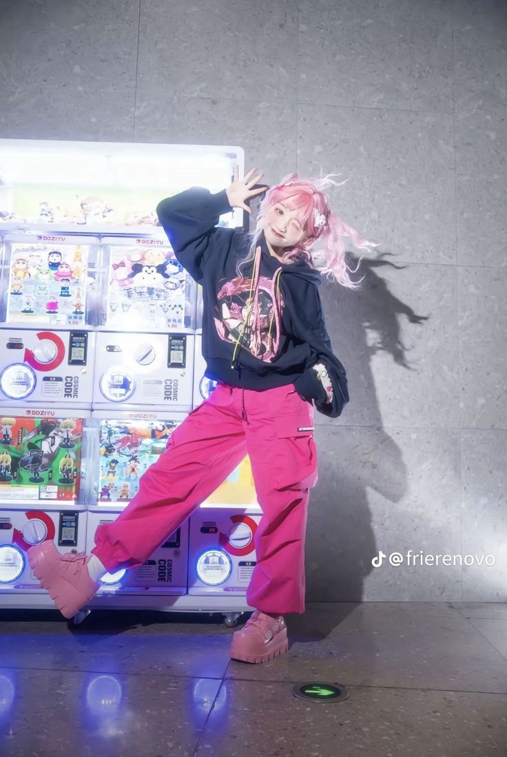 a woman with pink hair standing in front of a pile of cds