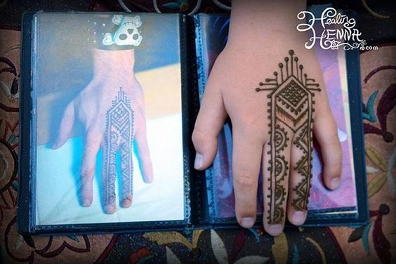 a person's hand with henna tattoos on their palm and hands holding an open book