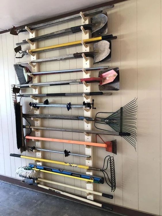 a wall mounted rack with many different types of utensils and brooms on it