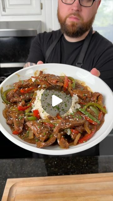 a man holding a plate with meat and vegetables on it