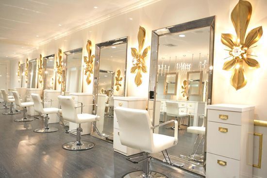 a room filled with lots of white chairs next to mirrors and gold accents on the wall