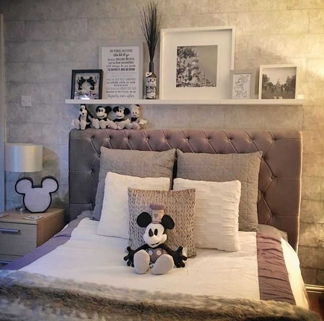 a bed with mickey mouse stuffed animal on it's head and pillows in the middle