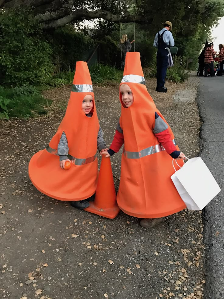 two children dressed in orange cones holding shopping bags