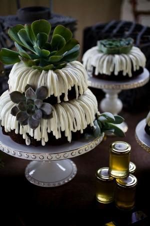 three tiered cake sitting on top of a table next to two bottles of olive oil