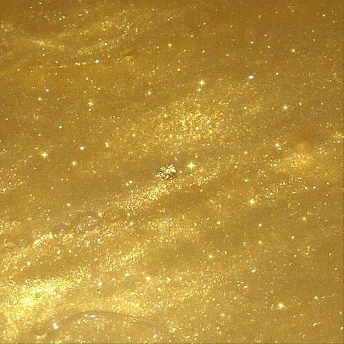 an image of some gold glitter in the air with stars and bubbles on it's surface