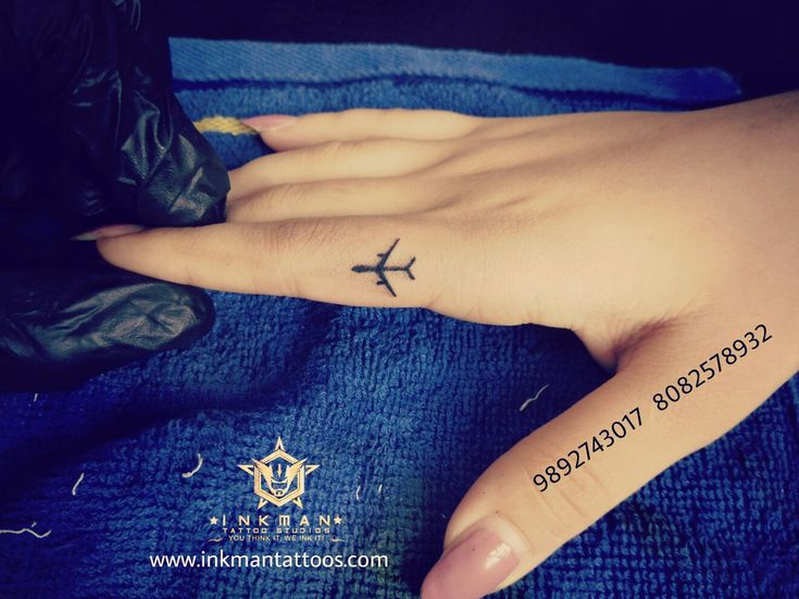 a woman's hand with a small airplane tattoo on it