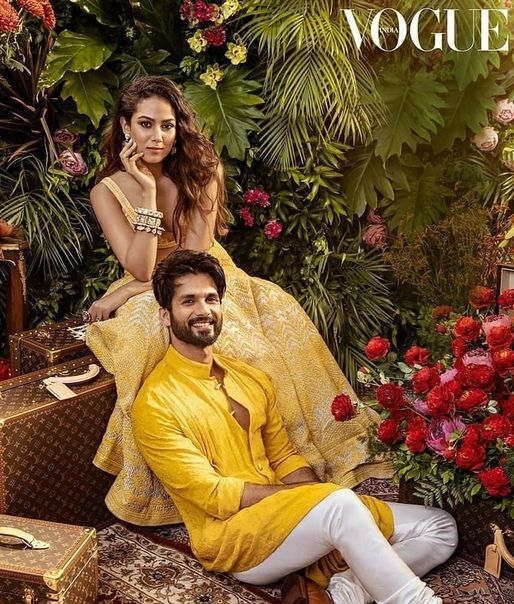 a man and woman sitting on suitcases in front of flowers