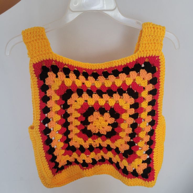 Elevate your summer style with our vibrant and playful Granny Square Tank Top, a crochet masterpiece featuring a harmonious blend of yellow, orange, black, and red. Crafted with meticulous attention to detail, this tank top is a versatile addition to your wardrobe, seamlessly transitioning from beach days to casual summer nights out. Key Features: Colorful Granny Square Design: The tank top showcases a stunning granny square pattern, with four lively colors - yellow, orange, black, and red. The intricate squares come together to create a visually appealing and dynamic garment that exudes charm and individuality. Tailored Fit for Medium and Large Sizes: Medium (Chest: 14.5 inches, Shoulder: 14.5 inches, Hem: 15 inches, Length: 15 inches) Large (Chest: 17 inches, Shoulder: 16.5 inches, Hem: Multicolor Vest Tank Top For Festival, Sleeveless Granny Square Tops For Spring, Multicolor Vest Top For Vacation, Casual Sleeveless Granny Square Top, Multicolor Crochet Sleeveless Tank Top, Orange Summer Crochet Top, Orange Sleeveless Crochet Top, Orange Tank Top For Beach, Orange Crochet Bohemian Top