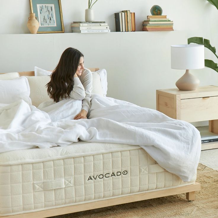 a woman laying on top of a bed covered in white sheets