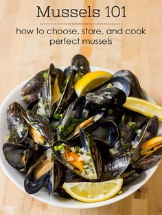 a white bowl filled with mussels and lemon wedges