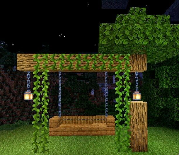 a bench in the middle of a park at night with lights on and vines hanging over it