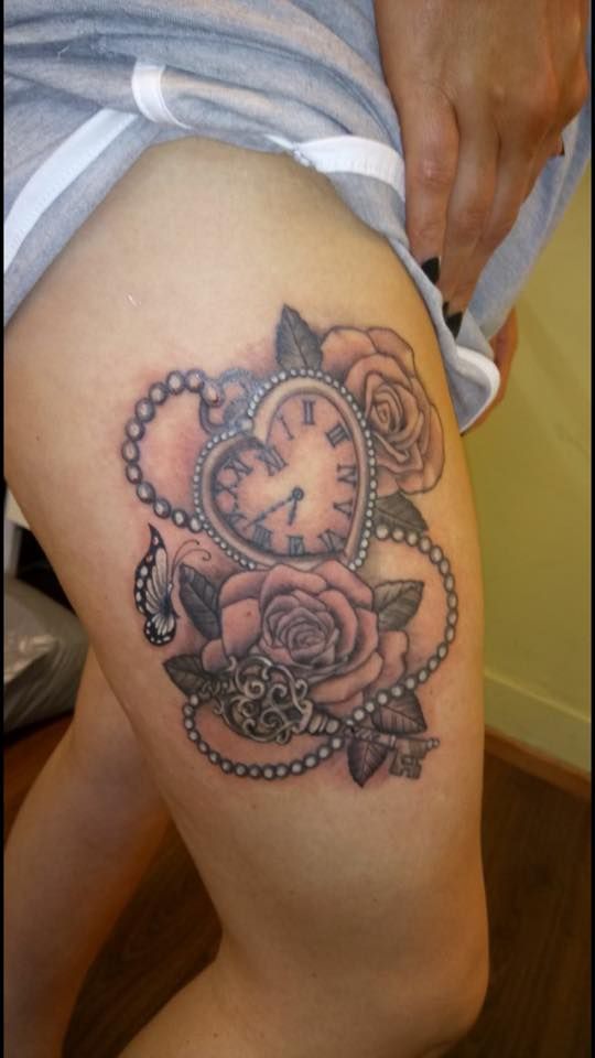 a woman's thigh with a clock and roses tattoo on the side of her leg