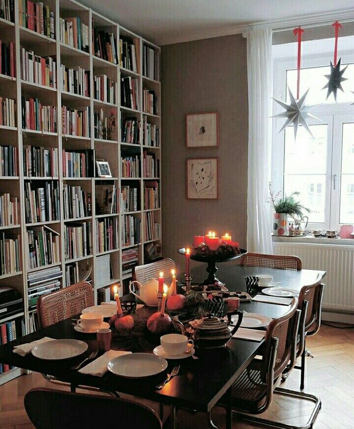 a dining room table is set with plates and candles in front of bookshelves