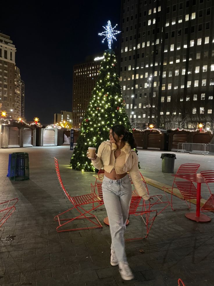 a woman standing in front of a christmas tree on the roof of a large building