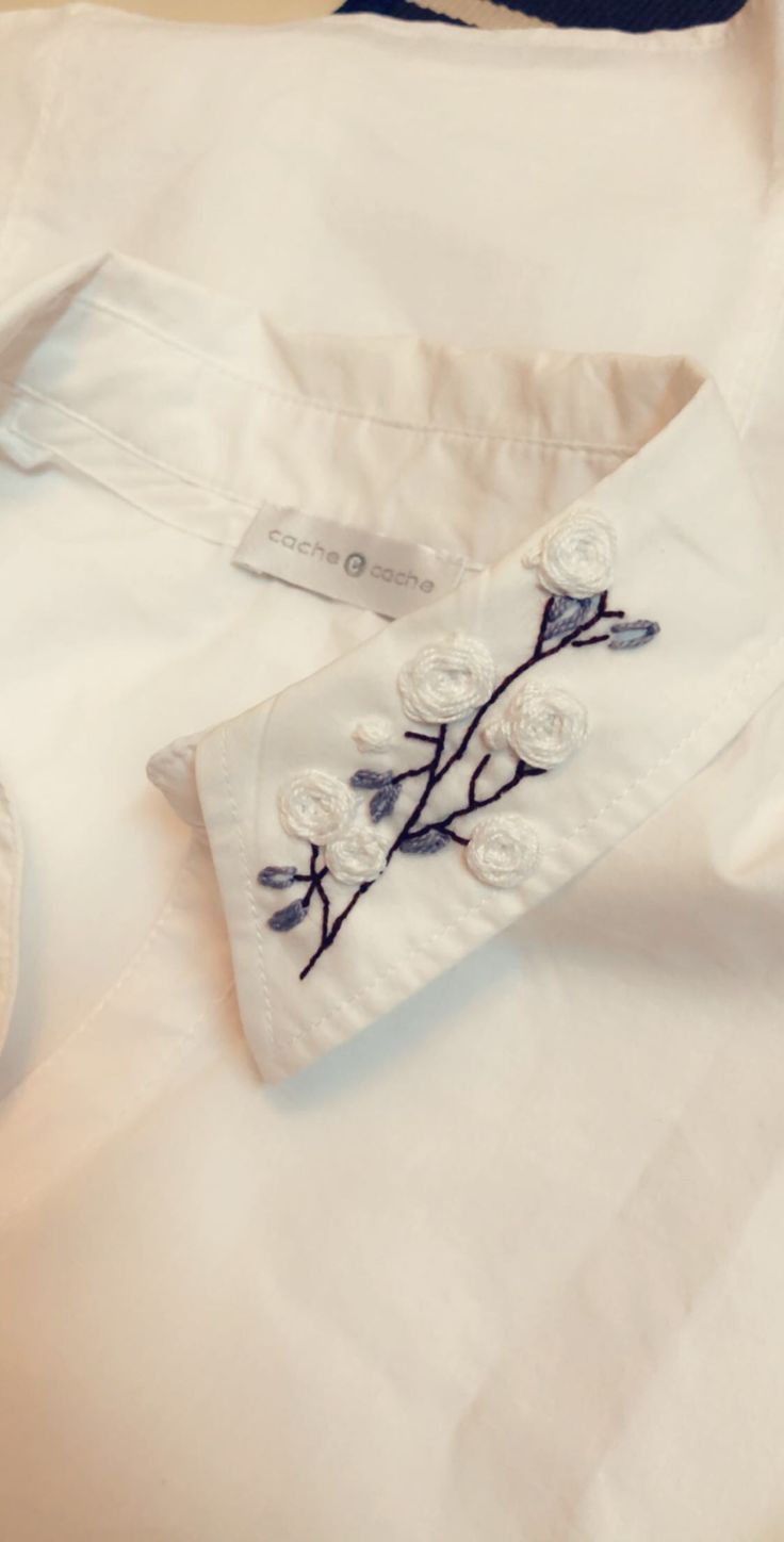 a white shirt with embroidered flowers on the collar