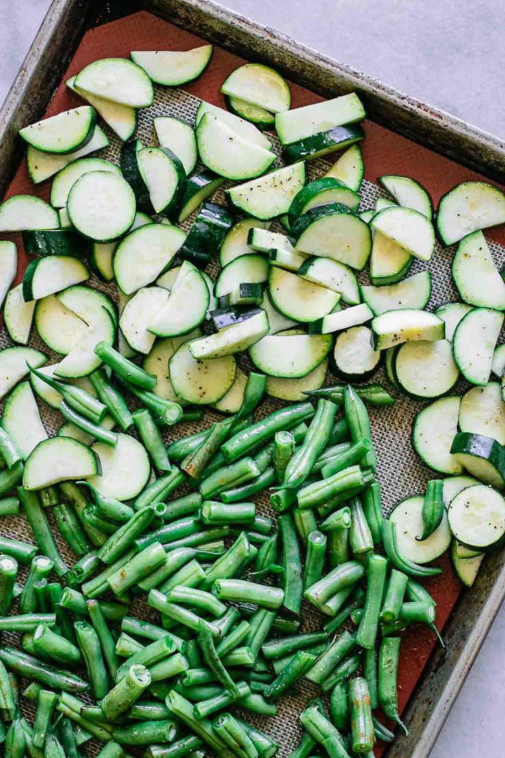 sliced cucumbers and green beans on a baking sheet