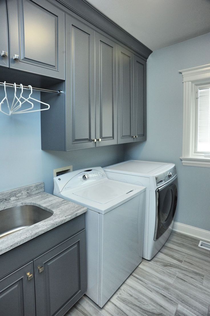 a washer and dryer in a small room with gray cabinets on the walls