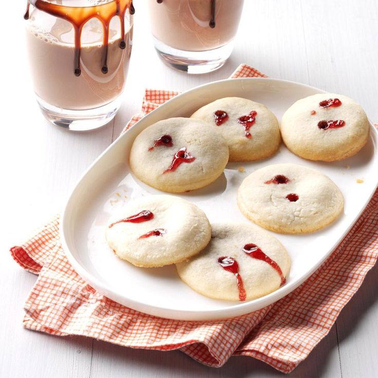 cookies with blood painted on them are sitting on a plate next to a glass of milk