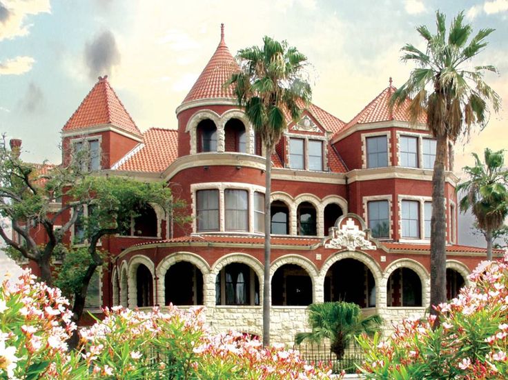 a large red brick building with lots of windows and palm trees in front of it