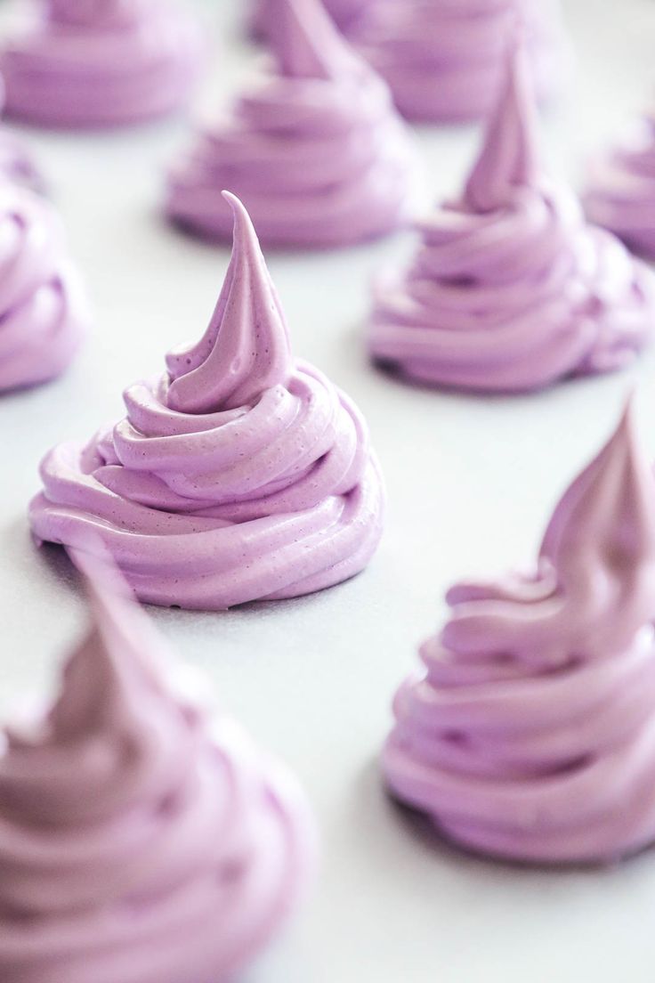 purple frosted cupcakes sitting on top of a white table