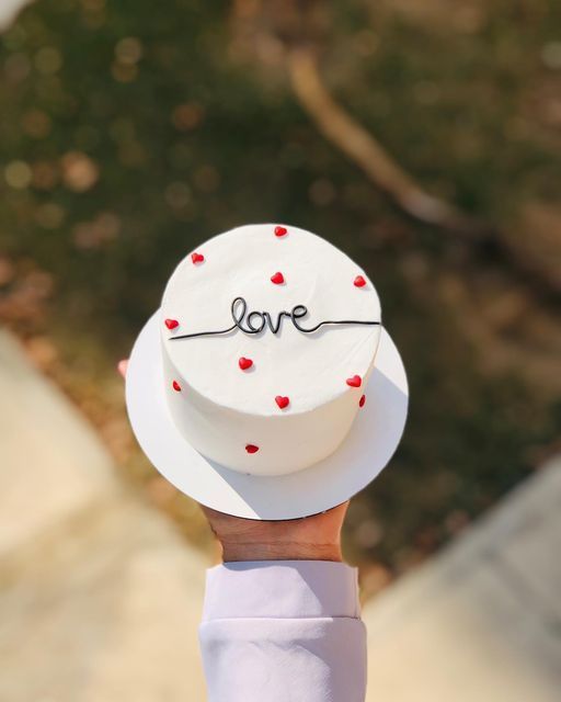 someone holding up a cake with the word love on it