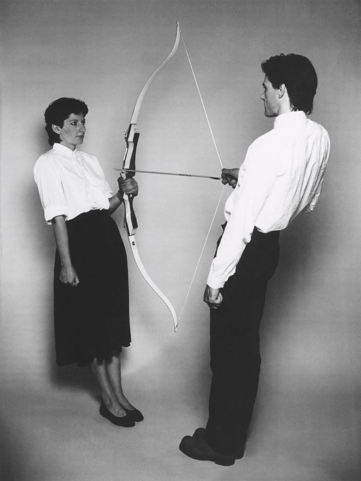 two people standing next to each other with a bow and arrow