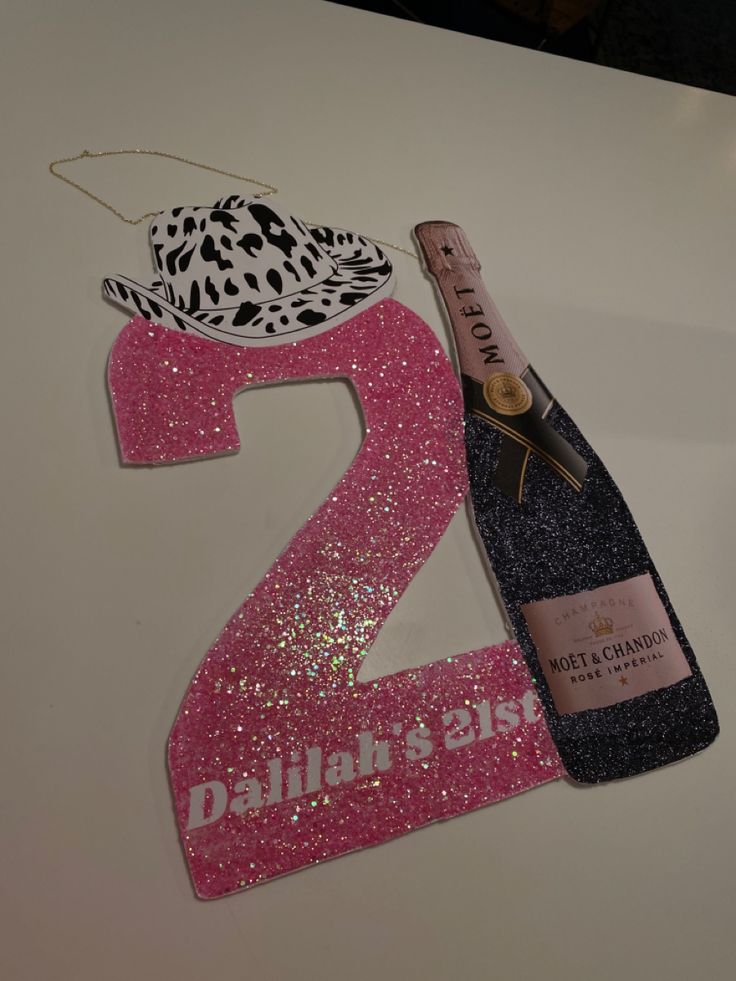 a pink and black number two with a bottle of wine next to it on a table