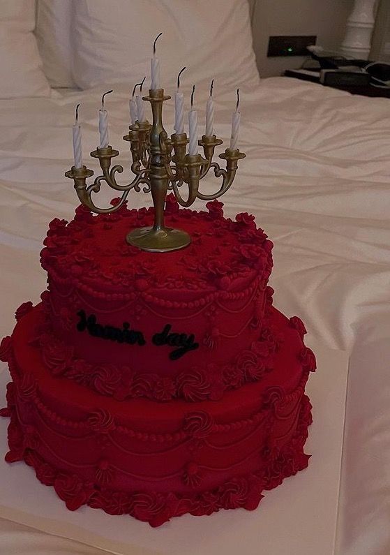 a three tiered red cake with candles on top