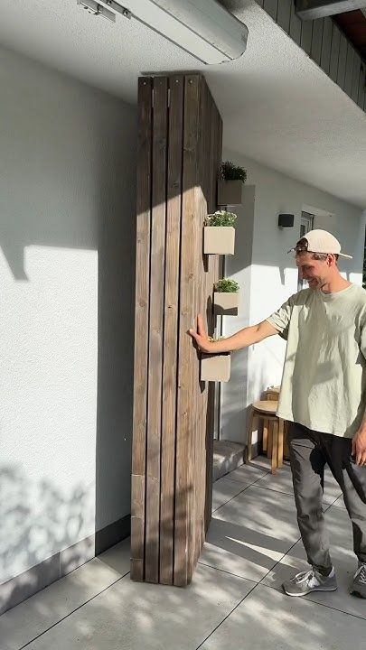 a man standing next to a tall wooden pole