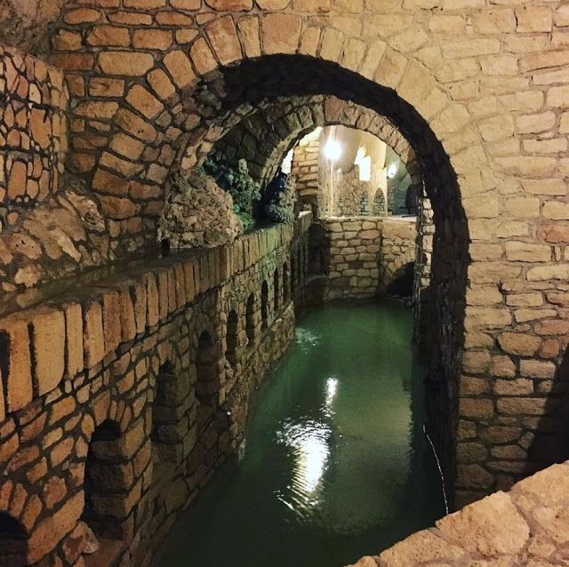 a tunnel that is next to a body of water in the middle of a stone wall