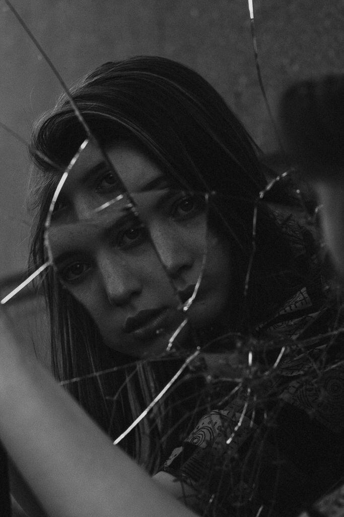 a woman looking through some barbed wire with her hand on the back of her head